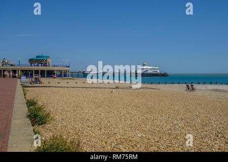 Eastbourne, Sussex, England, Großbritannien - 1 August 2018: Blick auf den Pier von der Promenade mit den Art-déco-Musikpavillon. Zwei leere Liegestühle sind offen auf Stockfoto