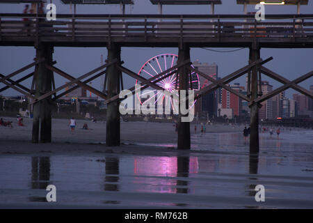 Riesenrad in Myrtle Beach, SC, USA, durch hölzerne Pfeiler des Piers gesehen Stockfoto