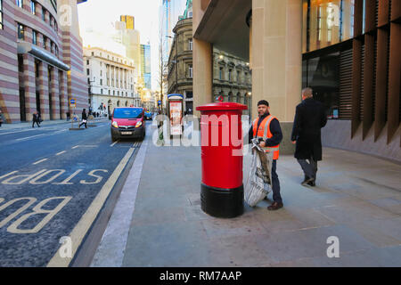 Postman über einen roten Briefkasten in City of London, London, England, UK zu leeren Stockfoto