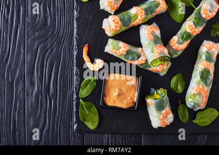 Frühlingsrollen, Vietnamesische Reispapier Brötchen mit Salat, Sojasprossen, Nudeln Nudel, Minze und Garnelen mit Erdnuss Soße auf schwarzem Schiefer tr Stockfoto
