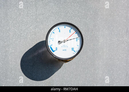 Nahaufnahme einer Runde Manometer an der Wand eines großen verzinktem Stahl Wassertank ausgerüstet, mit blauen Zahlen und zwei rote und schwarze Nadeln auf ein weisses Zifferblatt. Stockfoto