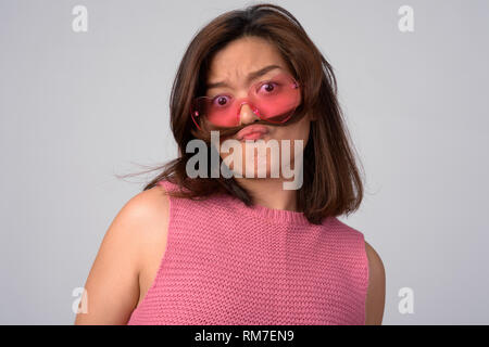 Junge schöne asiatische Frau mit Herz geformte Gläser mit Haar als Schnurrbart Stockfoto