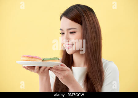 Asian Girl Show und Halteplatte voll mit lecker lecker aromatische Donuts in Smile Face isoliert. Stockfoto