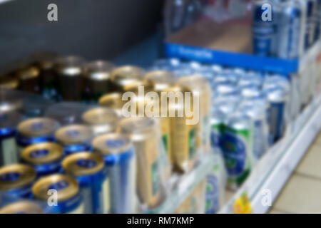 Verschwommenes Bild von Verpackungen mit Bier aus Dosen im Regal Stockfoto