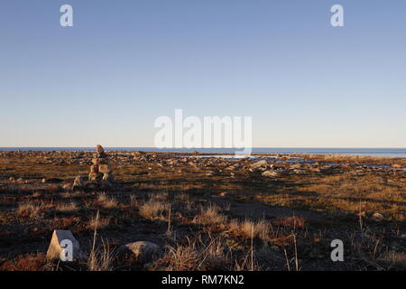 Inukshuk oder Inuksuk, ein Inuit traditionellen Marker auf einem felsigen Tundra in der Nähe von Wasser Ende Juni, Arviat, Nunavut, Kanada gefunden Stockfoto