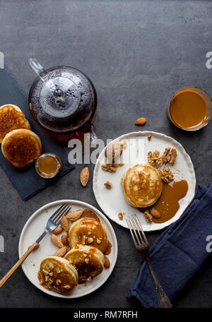 Festliche Komposition mit Pfannkuchen und kondensierten Karamell Milch auf schwarzen Hintergrund. Konzept der festlichen sprach Essen. Frühstück für zwei Personen Stockfoto