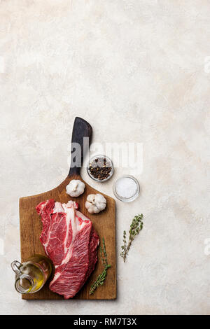 Rindfleisch mit Gewürzen und Knoblauch auf Holzbrett auf weißem Hintergrund. Konzept der gesunden Ernährung. Food Magazine. Ansicht von oben Stockfoto