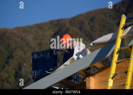 Ein Erbauer Hämmer Gebäude Papier als Team stellt das Dach auf einem großen kommerziellen Gebäude Stockfoto
