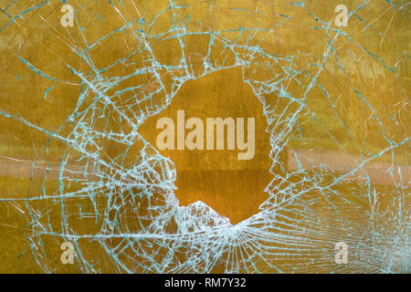 Zerschlagene Glasscheibe vor braunem Holz Stockfoto