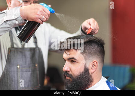 Friseur-Serie. Friseur sprying Wasser, Vorbereitung von Kunden für die Haare schneiden. Stockfoto