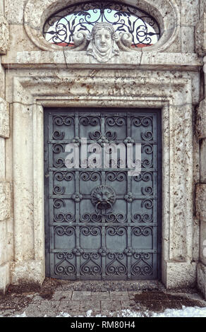 Architektonisches Detail: Renaissance bronze Portal mit einer elaborierten Türklopfer Löwenkopf geprägt durch ein Fenster in der Wand mit einem c eingerichtet überwunden Stockfoto