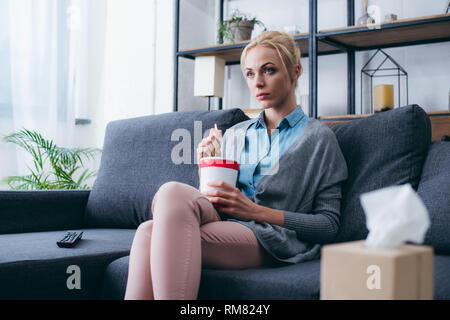 Traurige Frau Eis essen während siitng auf der Couch und Fernsehen zu Hause alleine Stockfoto