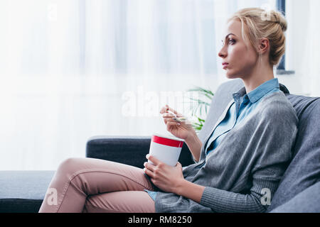 Traurige Frau Eis essen während siitng auf der Couch zu Hause alleine mit Kopie Raum Stockfoto