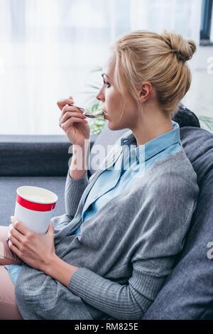 Deprimiert Frau Eis essen während siitng auf der Couch zu Hause alleine Stockfoto