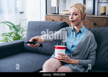 Frau Eis essen während siitng wathicng auf der Couch und TV zu Hause alleine Stockfoto