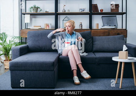 Deprimiert Frau Eis essen während siitng auf der Couch und Fernsehen zu Hause alleine Stockfoto