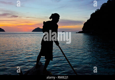 Die MOKEN MANN streers sein Boot an Sonnenuntergänge auf Ko Surin thailändischen Insel in Mu Ko Surin Nationalpark - THAILAND Stockfoto