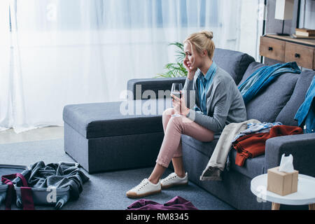 Deprimiert sitzende Frau mit einem Glas Rotwein im Wohnzimmer nach oben brechen mit Freund Verpackung Stockfoto