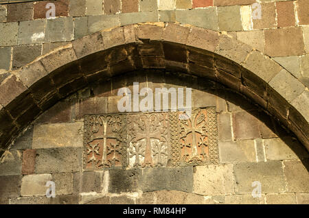 Detail mit geschnitzten Kreuze und Muster an der Wand unter dem oval Felsvorsprung über dem Eingangstor in das Gebiet von Geghard Kloster in Armenien Stockfoto