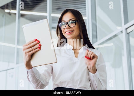Attraktive Geschäftsfrau mit einem digitalen Tablet während in einem großen Gebäude Stockfoto