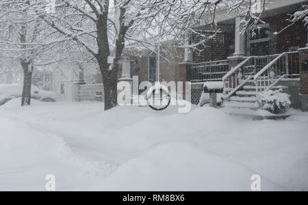 Eine malerische Straße, einen Gehweg mit Schnee bedeckt. Wir sehen ein Reifen auf einem Zweig hängend, aus dem Baum vor dem Haus. Ein kaltes Grauen Tag im Winter. Stockfoto