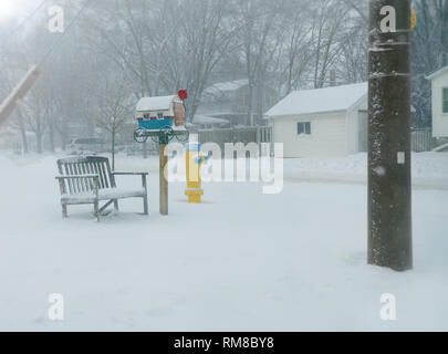 Winter in Stratford Ontario, Wir eine Mailbox, geformt wie ein Jahrgang Trainer sehen. Neben gibt es eine Bank, mit Schnee und einem gelben Hydranten gedeckt. Stockfoto