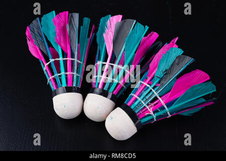 Bunte Federn im Badminton Federball. Mannschaft spielen. Der dunkle Hintergrund. Stockfoto