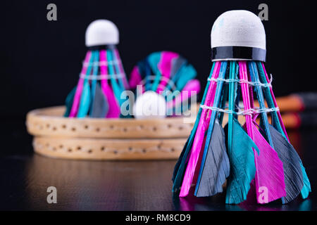 Bunte Federn im Badminton Federball. Mannschaft spielen. Der dunkle Hintergrund. Stockfoto