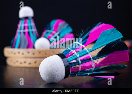 Bunte Federn im Badminton Federball. Mannschaft spielen. Der dunkle Hintergrund. Stockfoto