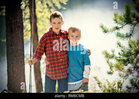 Porträt von zwei jungen Brüder mit Angelruten mit einem Arm um einander stehen. Stockfoto