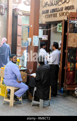 Ein paar Asiatische Männer sitzen um einen Tisch in einem Cafe in der Souk Al Kabir, auch als Dubai Alten Souk in Dubai in den Vereinigten Arabischen Emiraten (VAE) Stockfoto