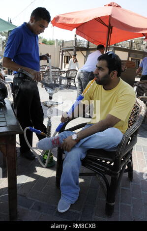 Ein saudischer Mann Uhren eine Shisha Bar assistant bereiten Sie eine fruchtgeschmack Substanz in eine Schüssel eine Shisha, eine Arabische rauchen Rohr an einer Shisha Bar in Duba Stockfoto