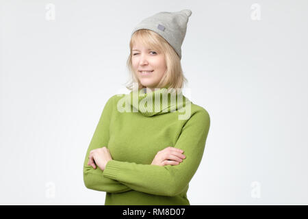 Fröhliche junge schöne Mädchen im grünen Pullover und Hut lächelnd winking Stockfoto