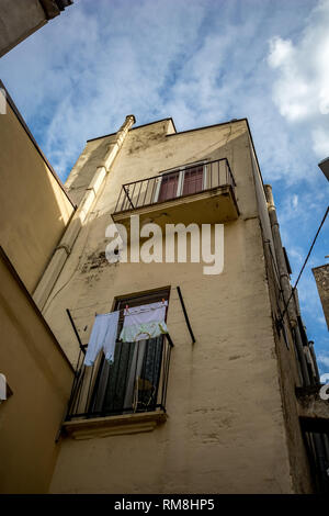 Blick auf die Straße von der historischen Altstadt von Altamura, Italien, Region Apulien, Wäsche trocknen auf Fenster von unten gesehen, Landschaft Sommer Tag mit Puffy weiße Wolken Stockfoto