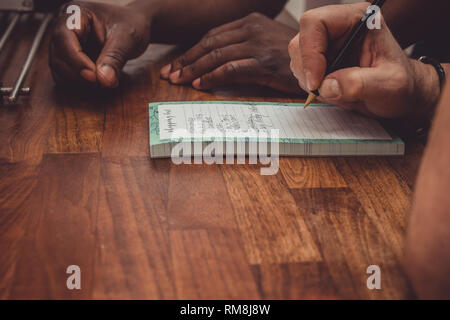 Ein interracial Gay Paare bilden eine Einkaufsliste für Lebensmittel auf einer hölzernen küche top zu Hause. Stockfoto