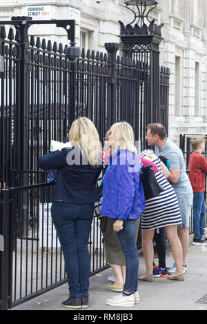 Touristen, die auf der Suche durch die eisernen Tore in der Downing Street. Stockfoto