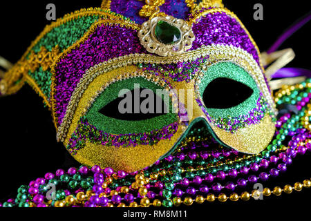 Jester Karneval Maske mit Perlen im Vordergrund auf schwarzem Hintergrund. Stockfoto