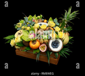 Holzkiste mit vielen exotischen Früchten und Blumen auf schwarzem Hintergrund Stockfoto