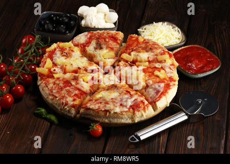 Leckere Pizza mit Ananas, Schinken schneiden, Speck in Scheiben schneiden, Mozzarella, pizza Sauce auf rustikalen Hintergrund für Fast Food und fertiges Konzept zu essen. pi Stockfoto