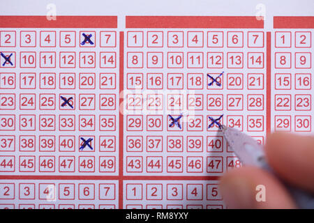 Nahaufnahme einer Person Nummer auf Lottoschein mit Stift markieren Stockfoto