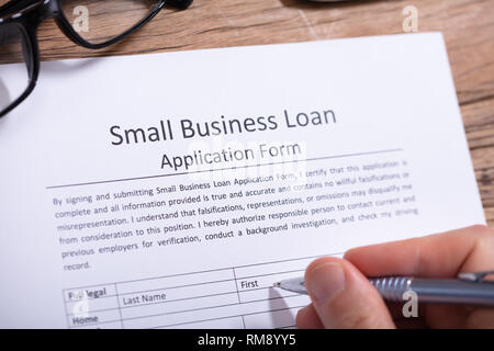 Nahaufnahme der Kaufmann Hand Befüllen Small Business Loan Application Form Stockfoto