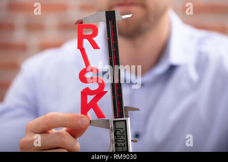 Menschliche Hand Messen rote Gefahr Wort mit digitalen elektronischen Messschieber Stockfoto