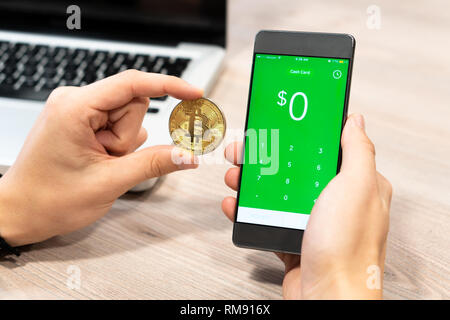 Cash App von Square inc angezeigt auf dem Smartphone durch menschliche Hand neben Bitcoin Münze und Computer Laptop - Slowenien 13.02.2019 Stockfoto