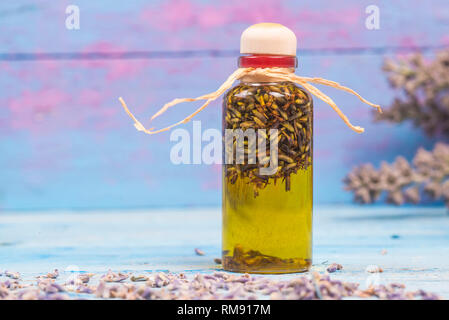 Lavendel Öl, Olivenöl aromatisiert in der Flasche mit Saatgut und Lavendelblüten auf hölzernen Tisch Stockfoto