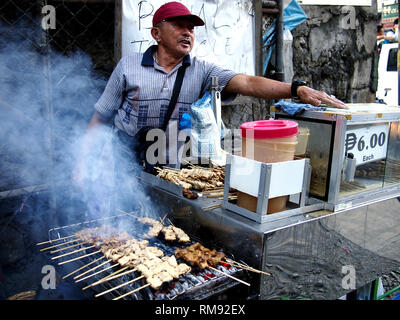 ANTIPOLO CITY, Philippinen - 26. JANUAR 2019: Straßenhändler Grill und verschiedene Fleisch Grill auf einem Bürgersteig auf ihre selbst gefertigten Lebensmittel verkaufen. Stockfoto