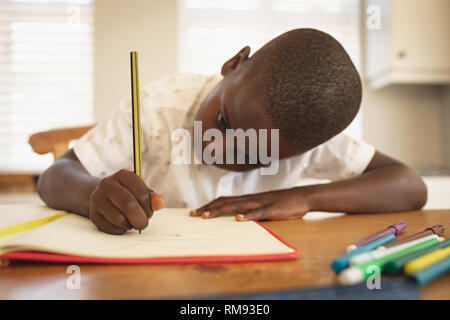 African American Boy Hausaufgaben am Esstisch in der Küche Stockfoto