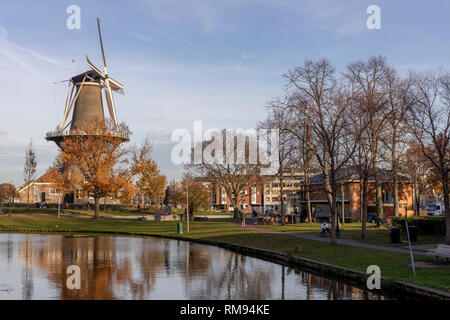 Horizontale Ansicht einer Windmühle in städtischen Umgebung in den Kanal mit klarem, blauem Himmel und Vogel Erstellen von Kreisen wider Stockfoto