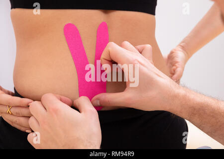 Nahaufnahme der Hand Anwendung Physio Tape auf der unteren Rückseite Stockfoto