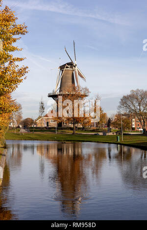 Vertikale Ansicht einer Windmühle in städtischen Umgebung in den Kanal mit klarem, blauem Himmel und Vogel Erstellen von Kreisen wider Stockfoto