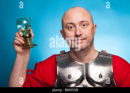 Ein römischer Soldat betrunken mit einem Glas Wein auf dem blauen Hintergrund. Stockfoto